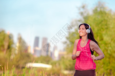 微笑的年轻女子在户外锻炼运动赛跑者短跑运动员女孩活力慢跑者身体公园护理运动装图片