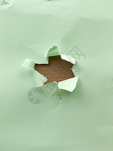 绿纸上有撕裂和弯曲边缘的洞图片