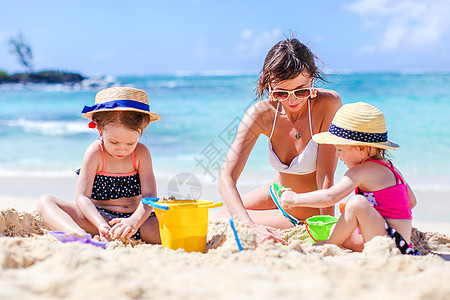 母亲和小女儿在热带海滩建造沙滩城堡海岸童年支撑女士情调孩子喜悦海岸线女孩家庭图片