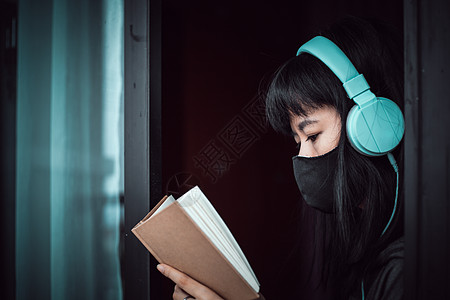 亚洲妇女为自我隔离和社会不和谐而住在家里的亚洲妇女阅读安全危险流感音乐停留耳机窗户悲伤感染图片