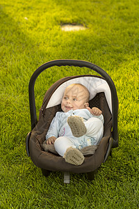 婴儿坐在草地上的汽车座椅上幸福运输快乐安全座位男生背景