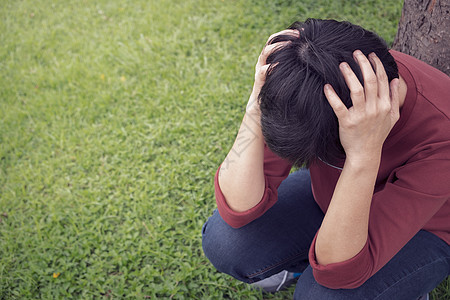一个人穿着红色衬衫 用压力抓着头顶公园焦虑眼睛哭泣女性骚扰头发女士疼痛成人图片