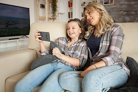 母亲和女儿穿相配衣服微笑互联网家庭妈妈幼儿园父母通话女士电话视频图片