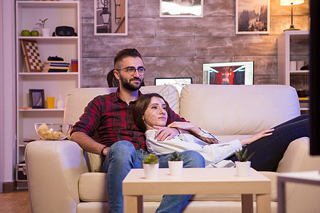 美丽的年轻夫妇在看他们最喜欢的电视秀时电视节目程序恋人娱乐专注房间电影女士公寓男人图片