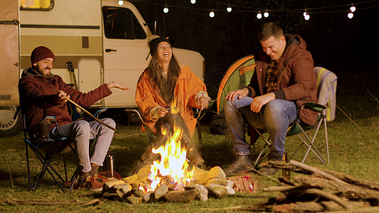 胡子人跟朋友说一个有趣的笑话 在营火周围森林椅子帐篷营地旅游朋友们灯泡星星空气团体图片