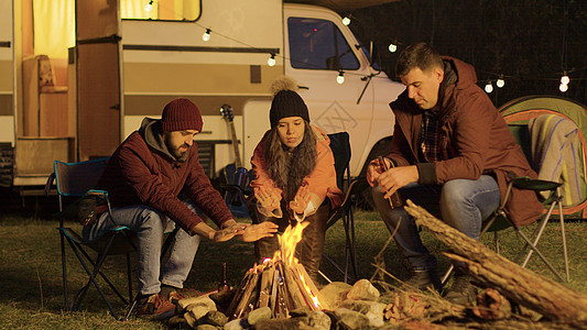 坐在营火周围露营椅上的亲密朋友帐篷火树林星星露营者灯泡旅游时间乐趣朋友们火焰图片