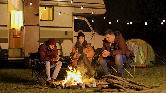 一群朋友在秋天寒冷的夜晚聚集在营地大火周围朋友们星星火树林乐趣帐篷胡子灯泡椅子旅游火焰图片