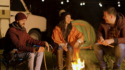 一群亲密朋友在秋天寒冷的夜晚 在营火周围一起放松旅游朋友们椅子胡子火树林时间乐趣营地帐篷故事图片