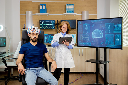 医生在脑扫描过程中跟踪男性病人 并在平板电脑上作笔记药品疾病屏幕诊所诊断活动监视器实验室头脑椅子图片