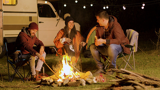 胡子人跟朋友说一个有趣的笑话 在营火周围空气灯泡团体房车星星帐篷火树林复古胡子椅子图片