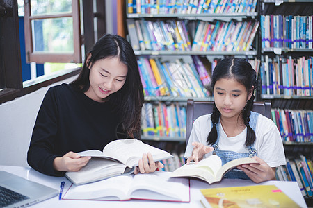 两名亚裔女学生阅读书籍和使用笔记本大学学习朋友家庭作业学校女孩考试知识成人幸福图片