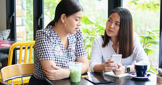 两位亚裔女性在咖啡馆喝咖啡及网上购物朋友们友谊互联网女孩幸福团体快乐杯子成人餐厅图片