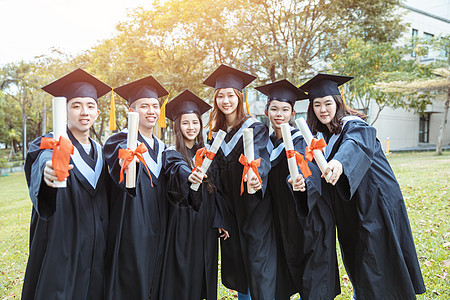 在大学校园持有文凭的毕业礼服中快乐学生人数百分比女士证书仪式团体微笑成就长袍学校多样性学士图片