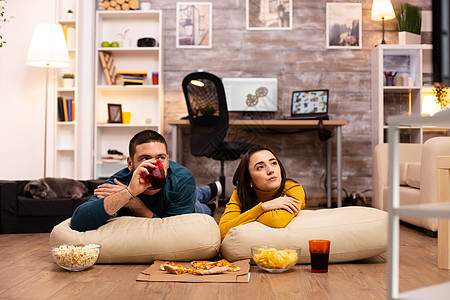 坐在地板上 在客厅看电视的一对夫妇公寓沙发食物女朋友闲暇房子扇子快乐成人小吃图片