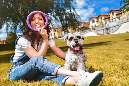 白人快乐的女人在公园里和她心爱的狗玩耍 爱动物的概念 最好的朋友 狗品种雪纳瑞 晴天天空卷曲房子拥抱女士头发女性友谊宠物朋友图片