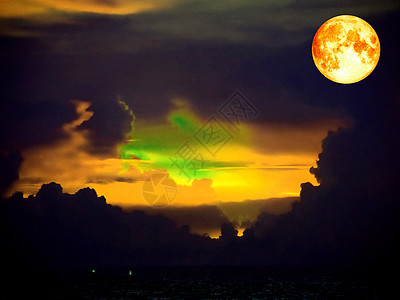 月亮血红橙色云 在海面的黑暗天空上图片