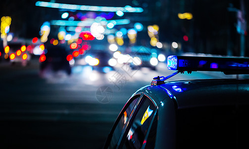 夜间巡逻夜警车灯在城市的夜间警车灯-有选择性地聚焦和bokeh背景
