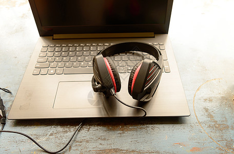 便携式耳罩式双耳 USB 耳机 带麦克风降噪和超声波音量调节耳机 适用于计算机 Skype 在早晨阳光下放在笔记本电脑上 音乐背图片