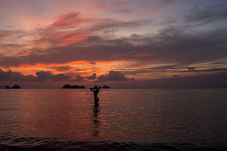 日落时 女人在海水或海洋中的轮廓海浪阳光生活海滩身体橙子乐趣天空女孩成人图片