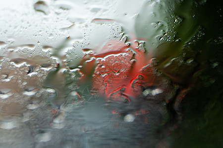 挡风玻璃上闪烁的雨滴 背景是夜间城市灯光街道旅行天气车辆交通驾驶风暴蓝色液体窗户图片