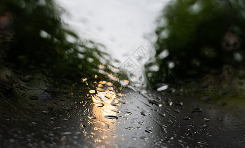 雨滴在挡风玻璃上 背景的夜晚城市灯光模糊不清风暴运输反射天气蓝色交通窗户车辆下雨驾驶图片