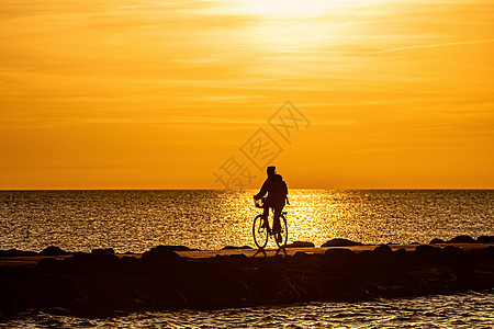 黄金时分人们在码头骑自行车的休眠钟太阳橙子夫妻日出天空阳光娱乐海岸地平线男人图片