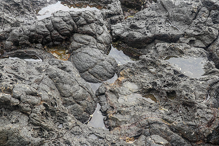 底部有白色沙子的岩石凹陷处充满了海水 在印度洋海岸巴厘岛印度尼西亚的熔岩床中挖掘出的小池塘 潮水在黑色岩石中挖出了小湖海岸石头卵图片