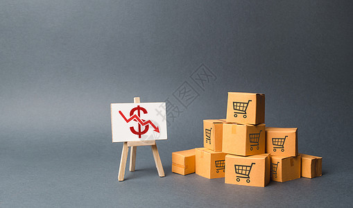 一堆纸箱和一个红色向下箭头的支架 商品和产品生产下降 经济低迷和衰退 消费需求下降 价格下跌 利润下降图片