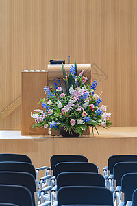 棕色木制舞台上摆放着一大束鲜花的讲台 可供讲师 主持人 发言人上台演讲图片