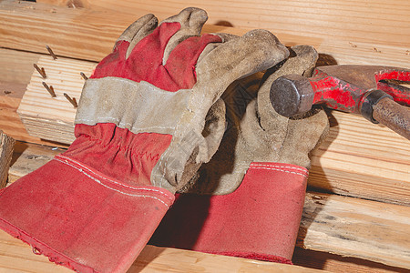 木板上放置的老旧生锈锤和建筑手套扳手维修硬件工具作坊工人工作锤子木工木头图片