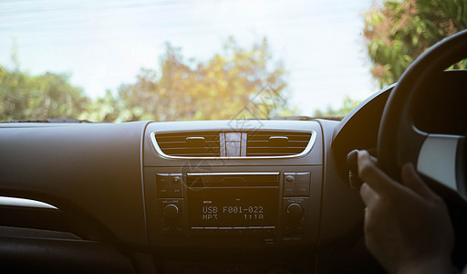 司机手在黑方向盘上 里面有仪表板镜子汽车乐趣运动速度自由运输车轮阳光沥青图片