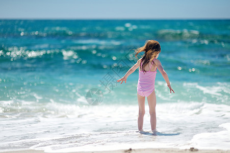 可爱的小女孩在海滩上玩蓝色童年海洋假期太阳天堂情调海岸孩子天空图片