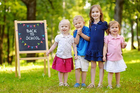 四个兴奋的小孩 在黑板旁边学生同学旗帜木板公园粉笔花环幼儿园团体女孩图片
