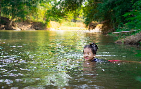 小亚洲女孩在河里玩 阳光照耀图片