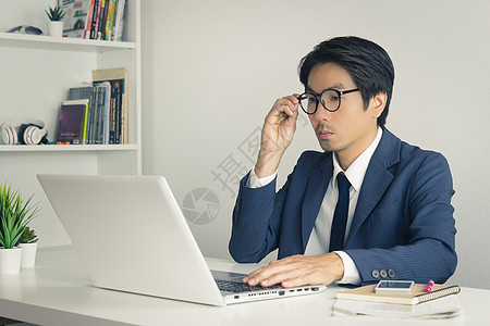 亚洲财务顾问或亚洲咨询商务人士考虑销售男性理财套装技术商务互联网手机工人电脑图片