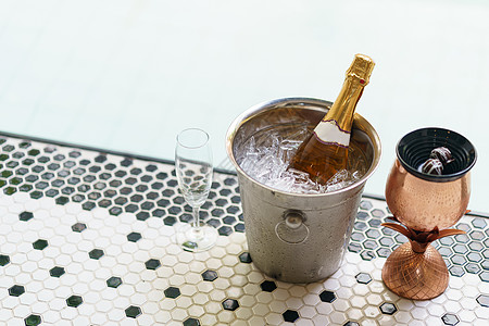 冰桶香槟瓶和泡泡池附近的两个杯子蜜月原野水池旅行饮料游泳夫妻游泳池浴缸周年图片