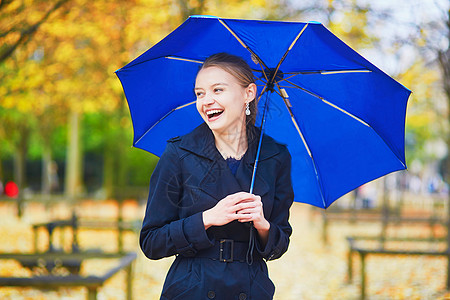 秋天或春季下雨日 在卢森堡巴黎花园的卢森堡花园中带蓝伞的年轻女子季节园艺女孩花园预报橙子女士沉淀树叶公园图片
