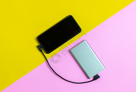 智能手机手机通过移动电源粉红色和黄色背景为电池充电展示收费电缆细胞充值粉色力量充电器技术电话图片
