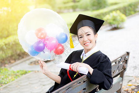 穿着学术服和学校服装的年轻快乐女毕业生肖像召集微笑女性大学气球文凭成功学习研究生女士图片