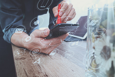 商务人士手拿笔使用智能手机 仅移动支付服务工作电话笔记本男人网络营销信用桌子木头背景图片
