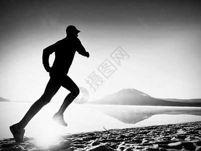 活跃男子在湖边锻炼和伸展的轮光环绕着月光健康阴影短跑跳远慢跑者风景太阳沙径日落爬坡图片