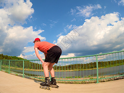 在桥上穿红T恤和黑裤子滑冰的内线滑冰机后视线图片