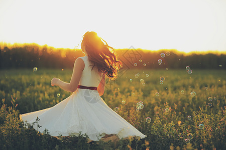 气泡里女孩美丽的女孩在公园里跳舞 在日落的灯光下 肥皂泡沫 幸福的概念场地婚姻喜悦女士气泡女性微笑阳光飞行草地背景