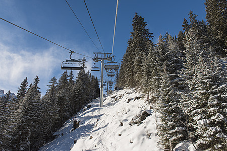 高山坡上带滑雪电梯的全景松树缆车山脉胜地天空山腰蓝色天线座位运输图片