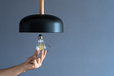 特写 手会改变一个灯泡 在时尚的阁楼灯 螺旋丝灯 现代室内装饰生态天花板家庭力量活力电气技术金子服务玻璃图片