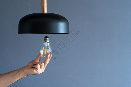 特写 手会改变一个灯泡 在时尚的阁楼灯 螺旋丝灯 现代室内装饰技术服务生态电气经济天花板玻璃活力白炽灯阁楼图片
