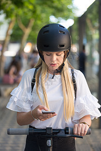 妇女使用智能手机 并租赁现代电动摩托车和应用程序;城市交通概念 (b)图片
