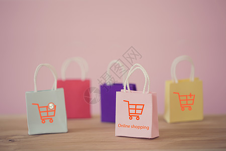 在线购物和电子商务概念 纸质购物袋 桌上有购物车图标 在线商店被认为是企业家和客户之间进行商品交易的另一种媒介图片