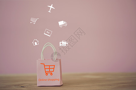 在线购物和电子商务概念 粉色纸质购物袋 桌上有购物车图标 在线商店被认为是企业家和客户之间进行商品交易的另一种媒介图片