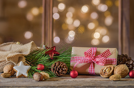 圣诞礼物 带有饼干 坚果和装饰品的圣塔袋装在木桌布满闪亮灯光背景的木纸上图片